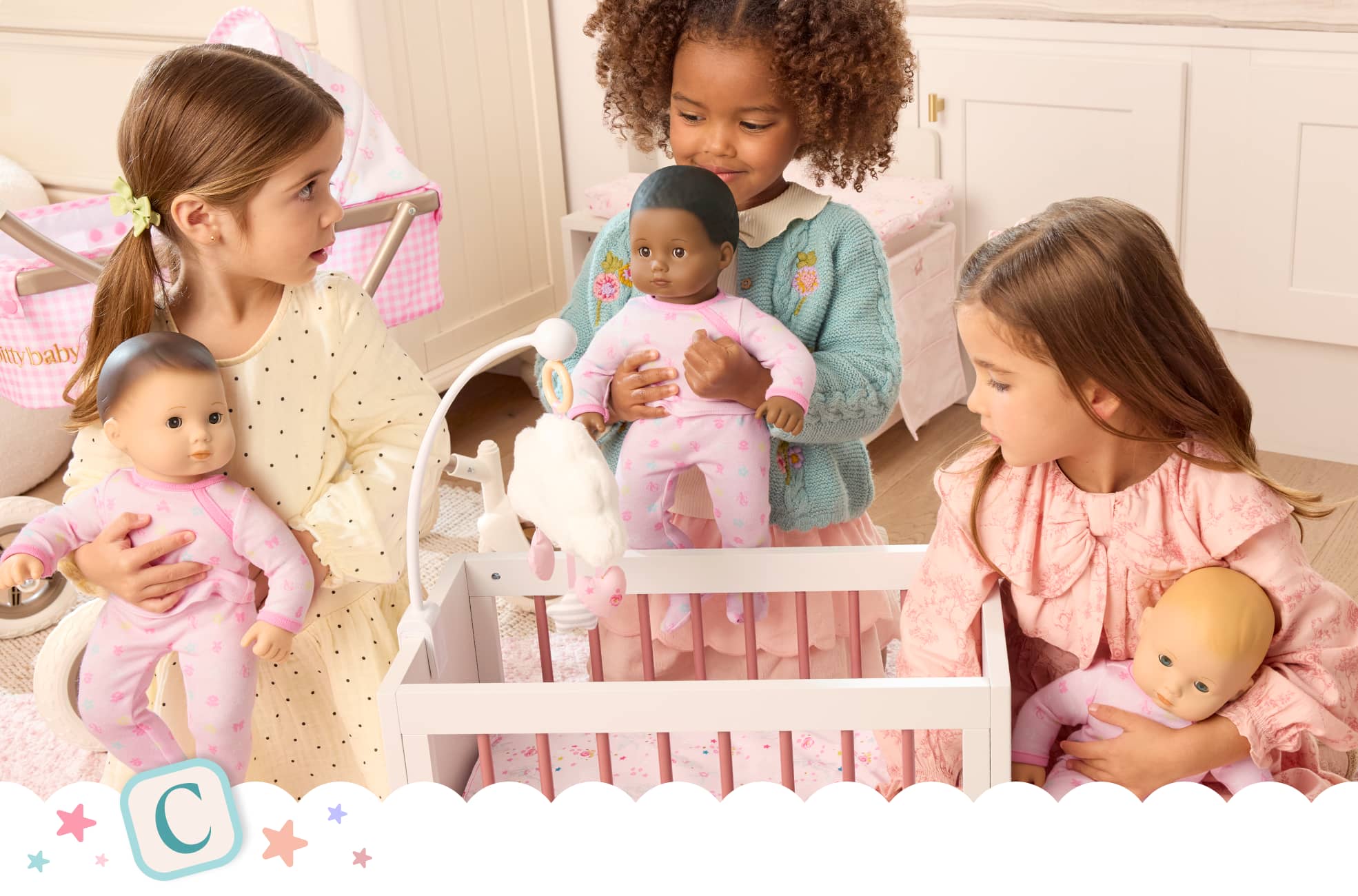 Three young girls with their Bitty Baby dolls next to a crib and stroller