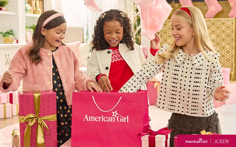 Three girls opening an American Girl gift bag