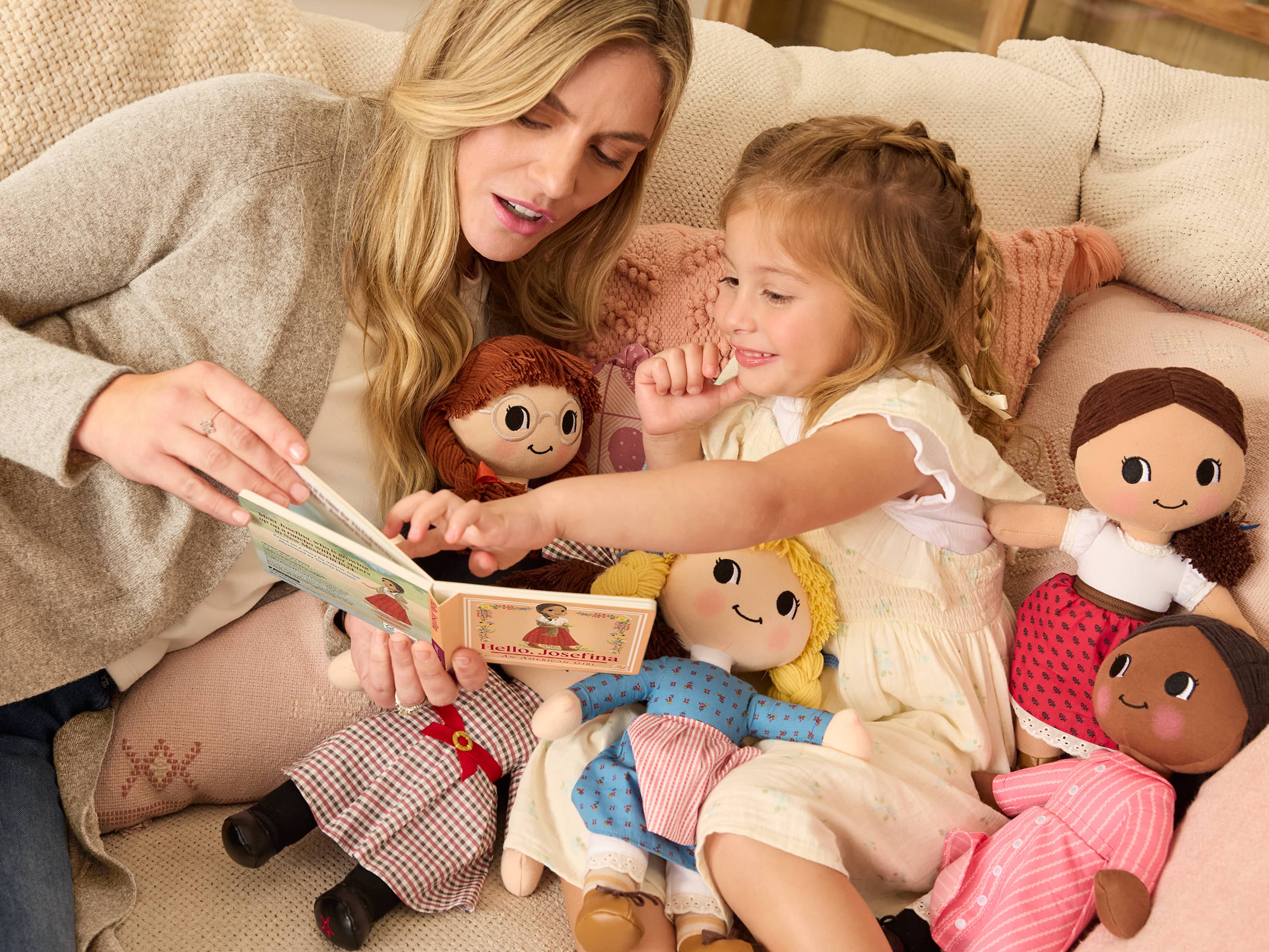 Girl reading Hello Josefina book with her mother surrounded by Historical Character plush dolls
