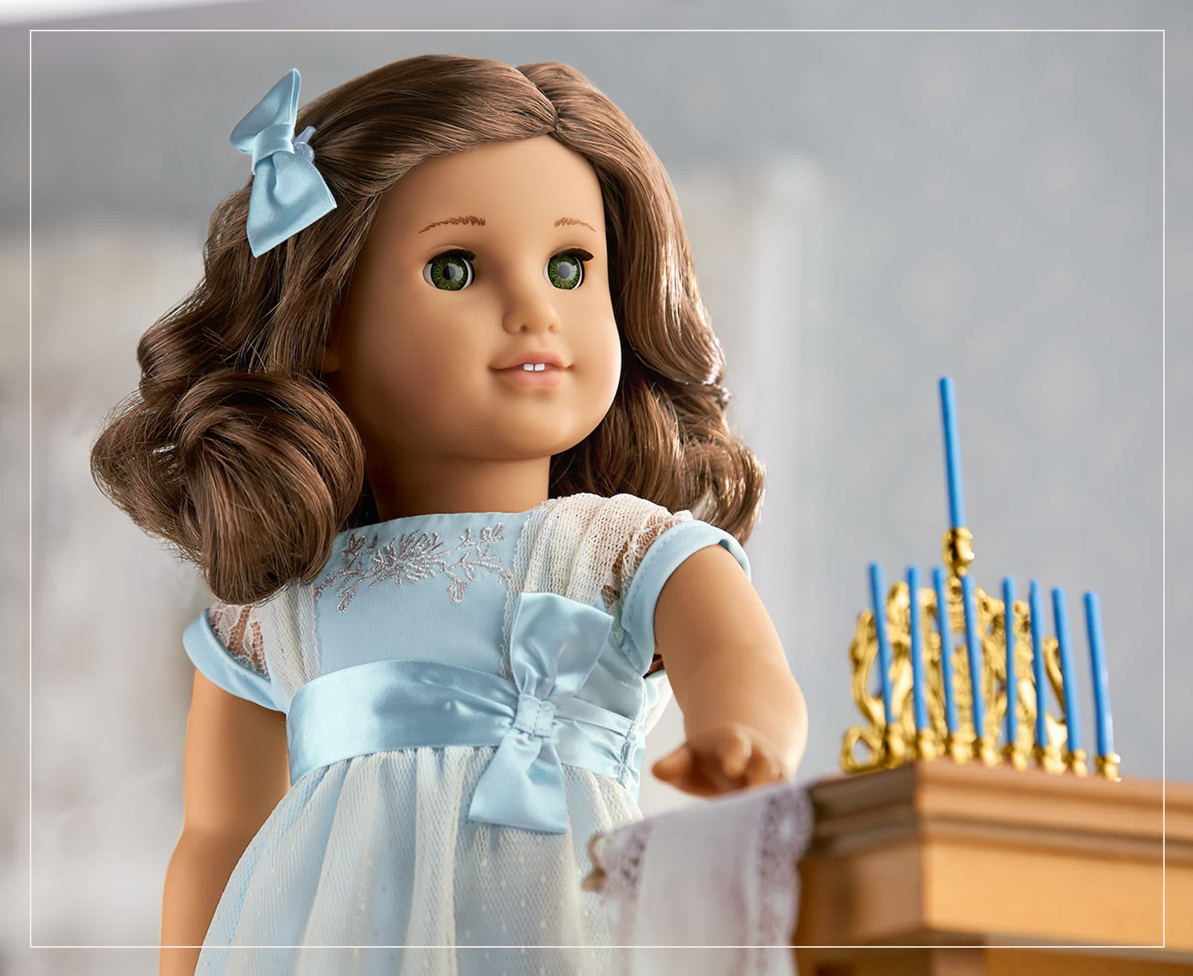 Rebecca Rubin doll standing next to blue Hanukkah candles