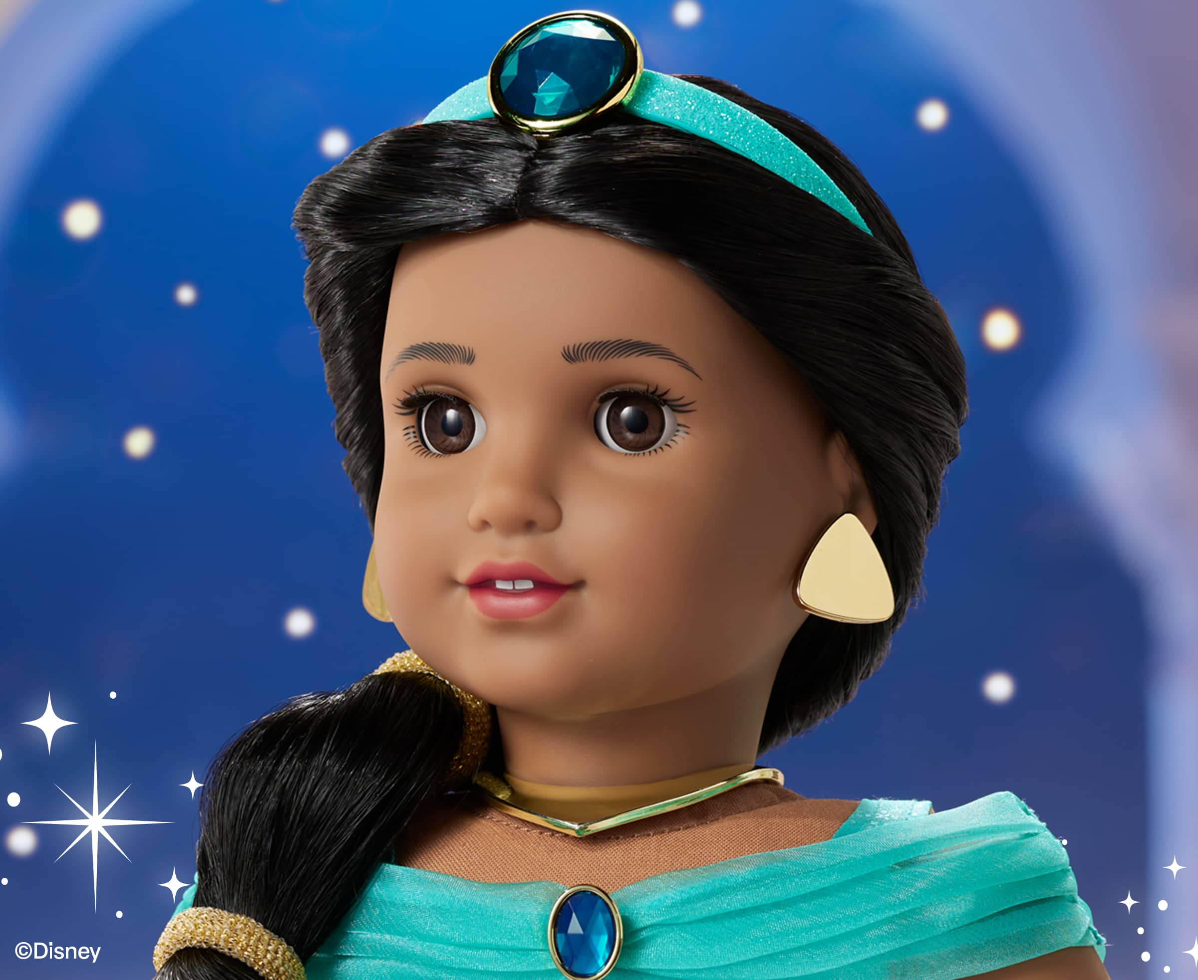 Up close American Girl Jasmine doll, featuring her light blue headband, brown, eyes, and gold colored earrings.
