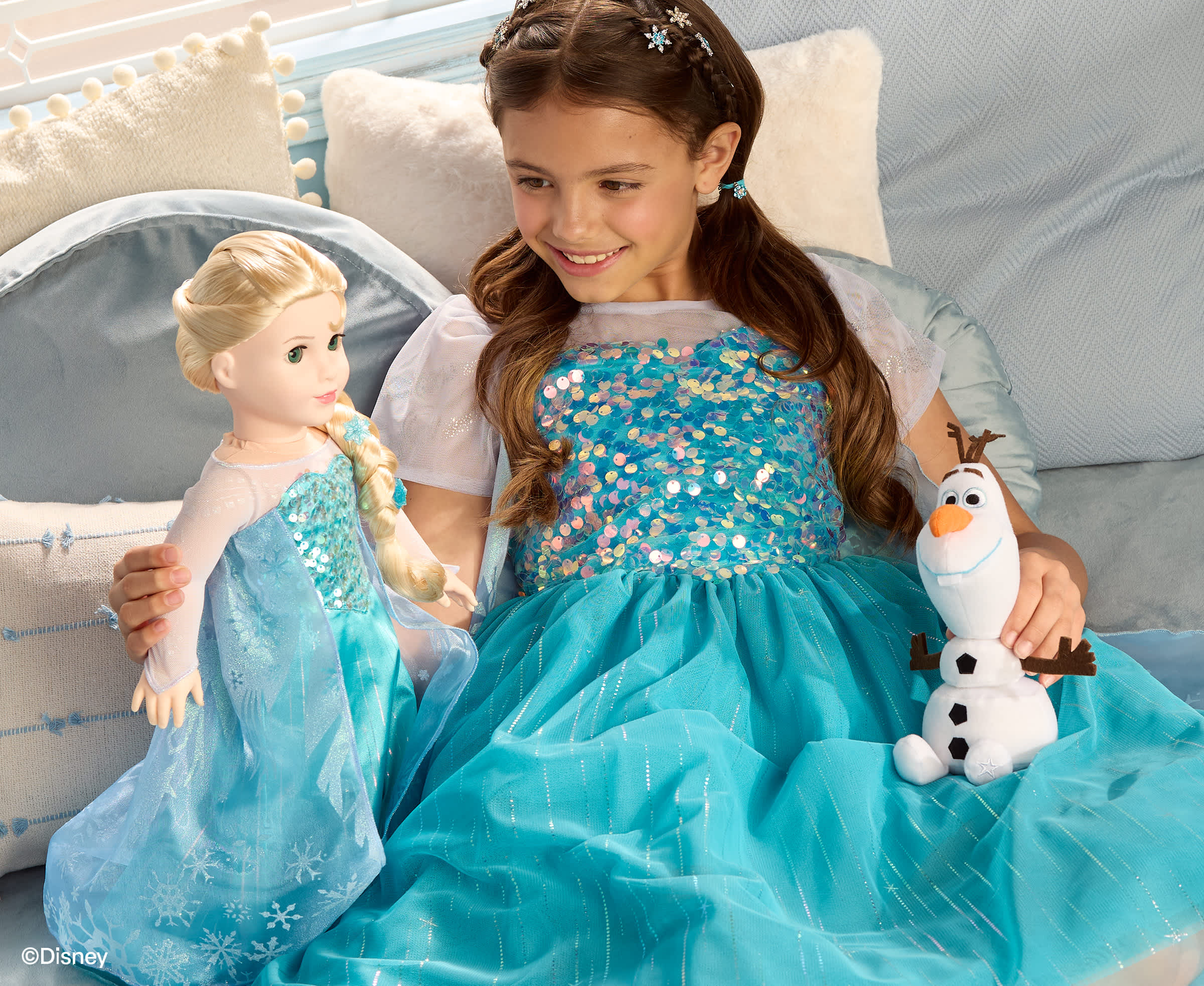 Girl and Elsa doll wearing matching blue dresses